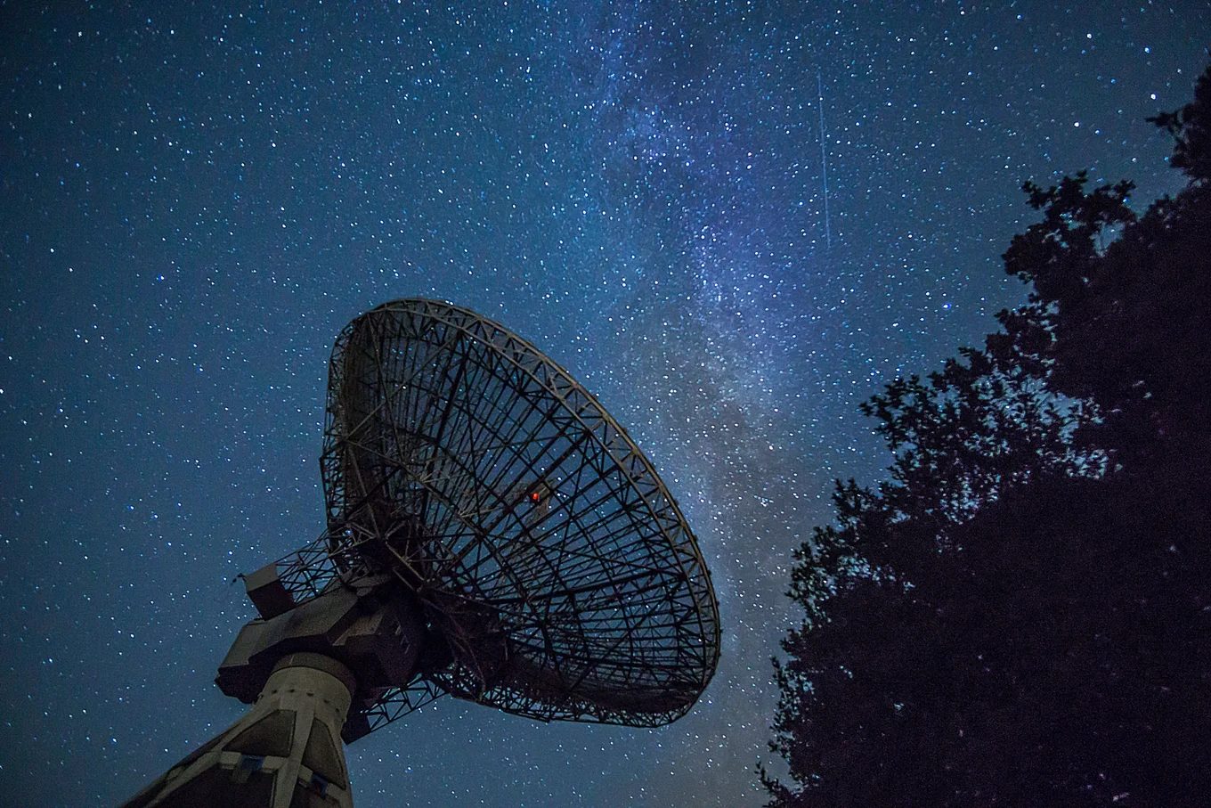 Satellite dish with starry sky backdrop.